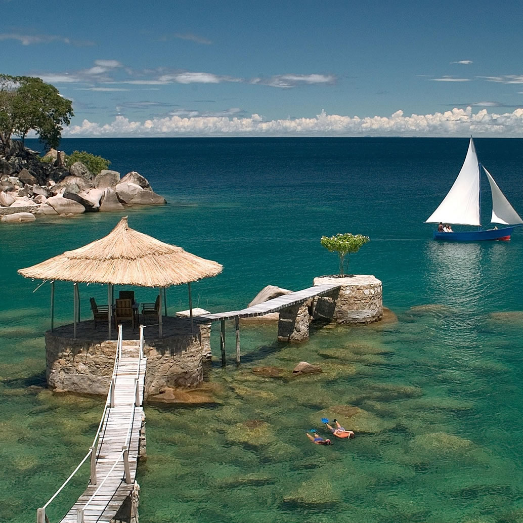 A beautiful image of Lake Malawi with an island, walkway and a sailboat