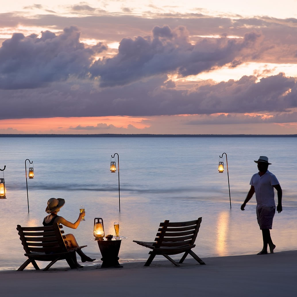 Guests on a beautiful white sand beach enjoying sundowners overlooking the Indian Ocean in Mozambique